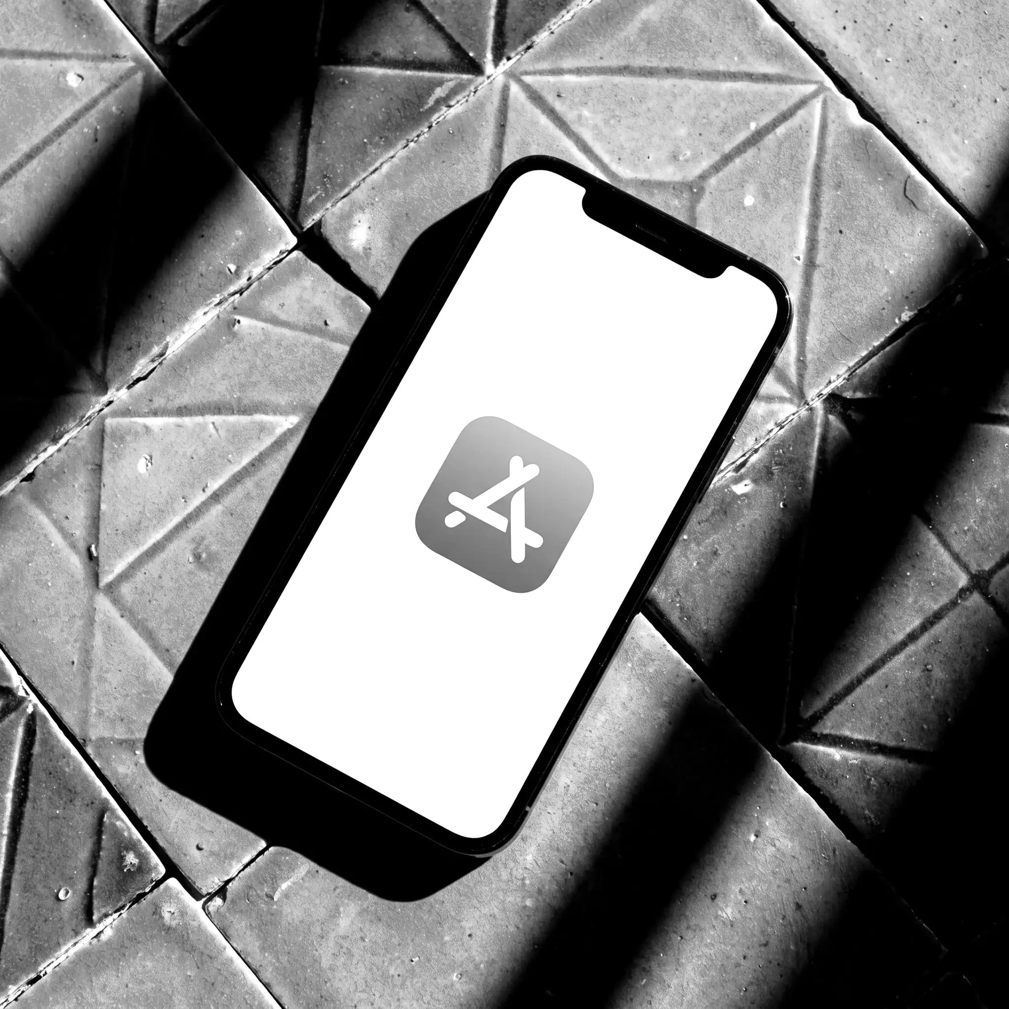 iPhone auf blauen Fliesen, App Store geöffnet